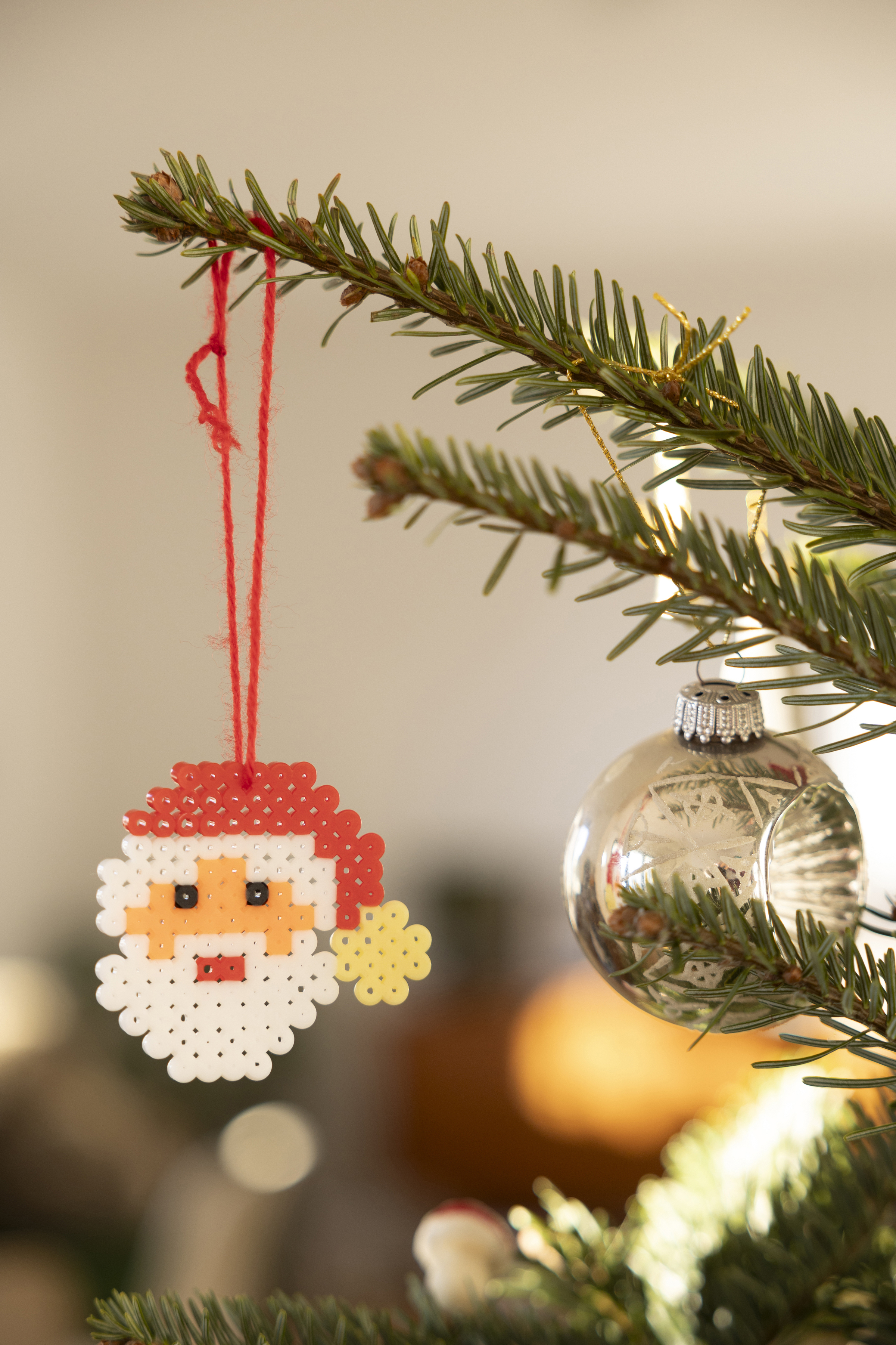 En pärlad jultomte som hänger som dekoration i granen. 