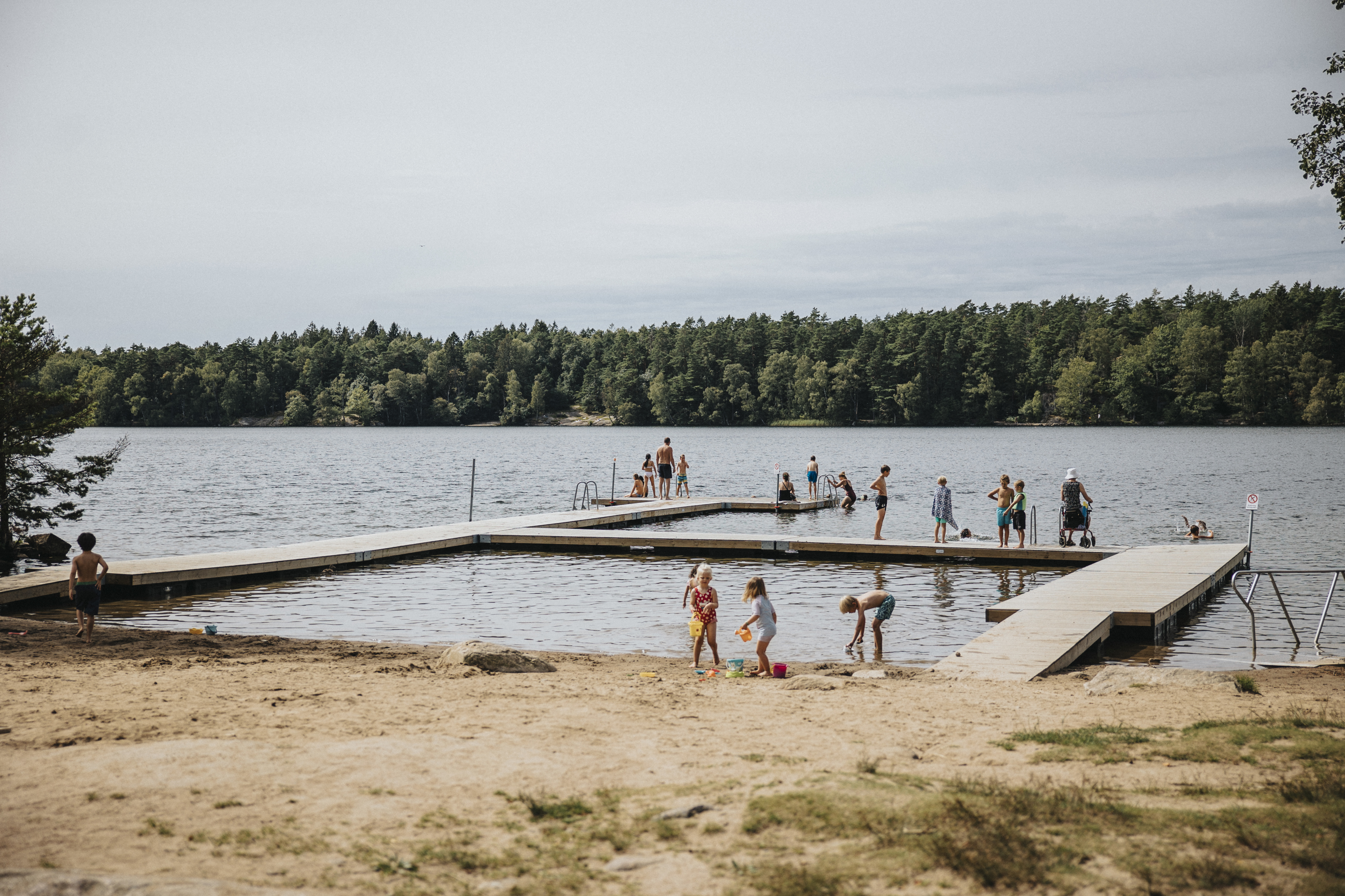 En brygga vid en sjö med sandstrand i förgrunden