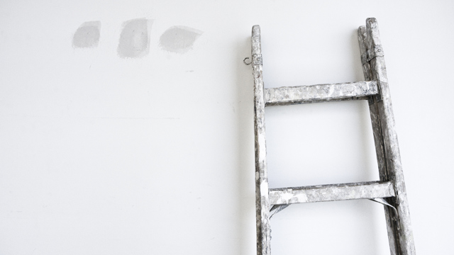 En vägg med spackel och en stege lutad mot.