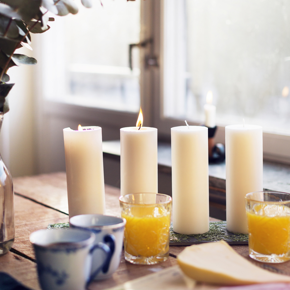 Fika i advent. Kaffe, juice, smörgåsar och fyra stora ljus på en lång bricka.