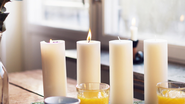 Fika i advent. Kaffe, juice, smörgåsar och fyra stora ljus på en lång bricka.