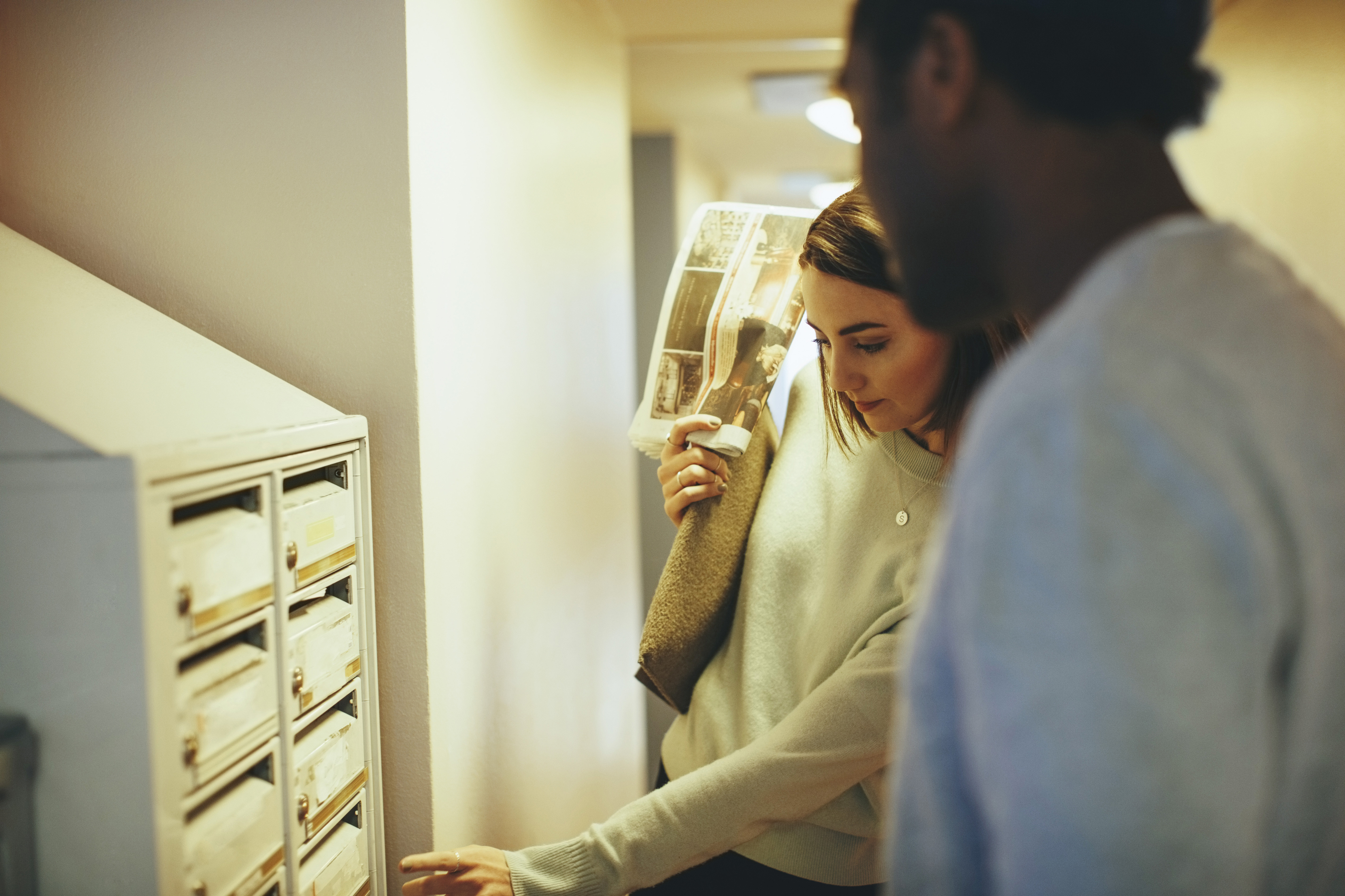 Två personer hämtar post vid sin postbox i ett flerfamiljshus