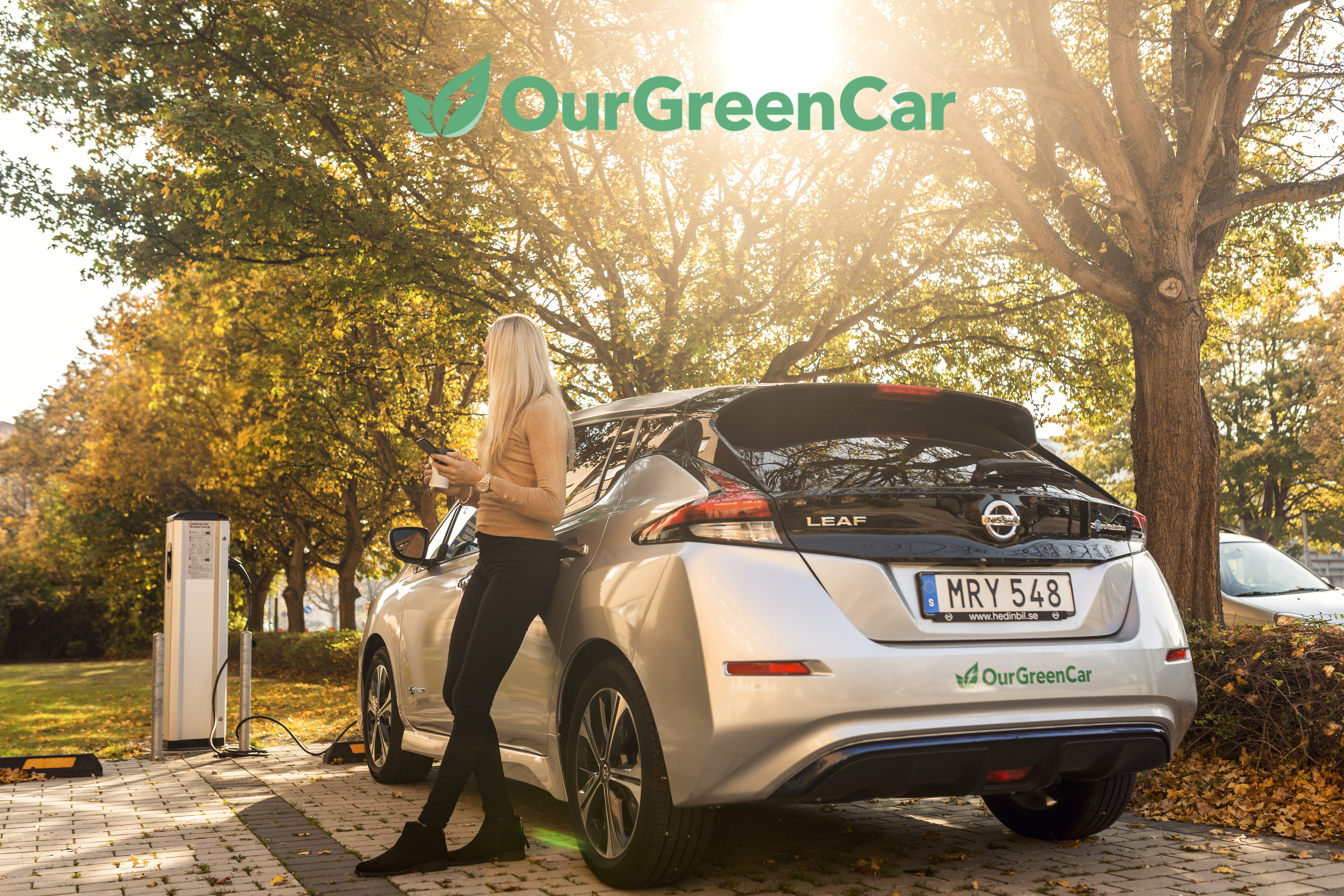 En kvinna väntar på att en elbil ska ladda klart 