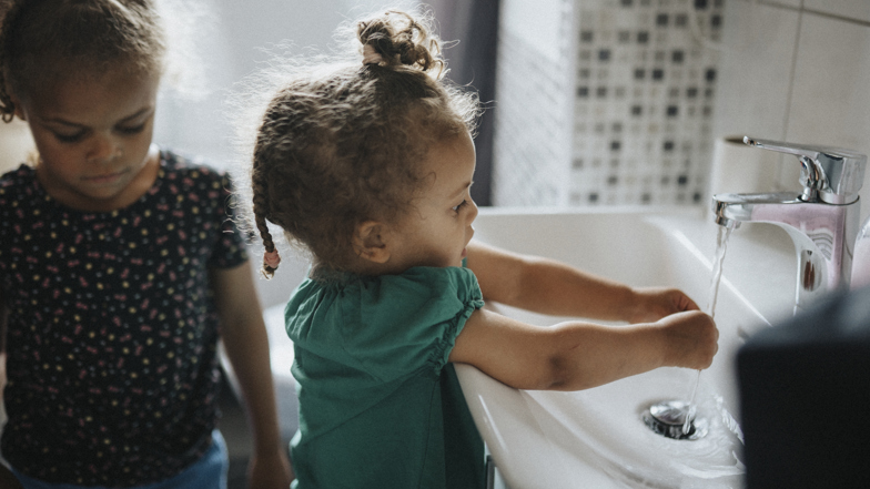 Ett barn tvättar händerna i ett handfat 